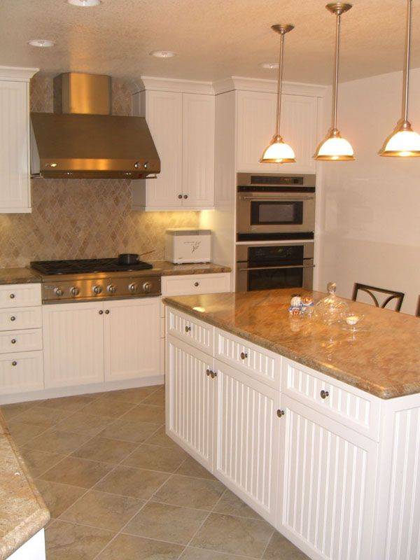 Kitchen with beige granite counters travertine tile floor and rich wood cabinets