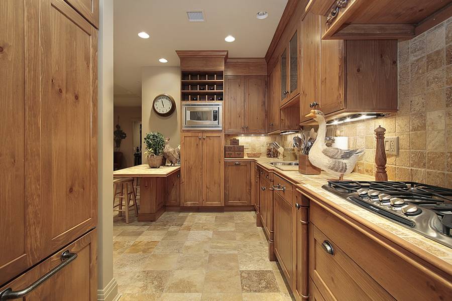 Kitchen with beige granite counters travertine tile floor and rich wood cabinets