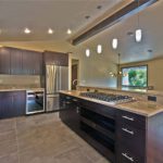 Kitchen with open layout, limestone flooring and dark cabinetry