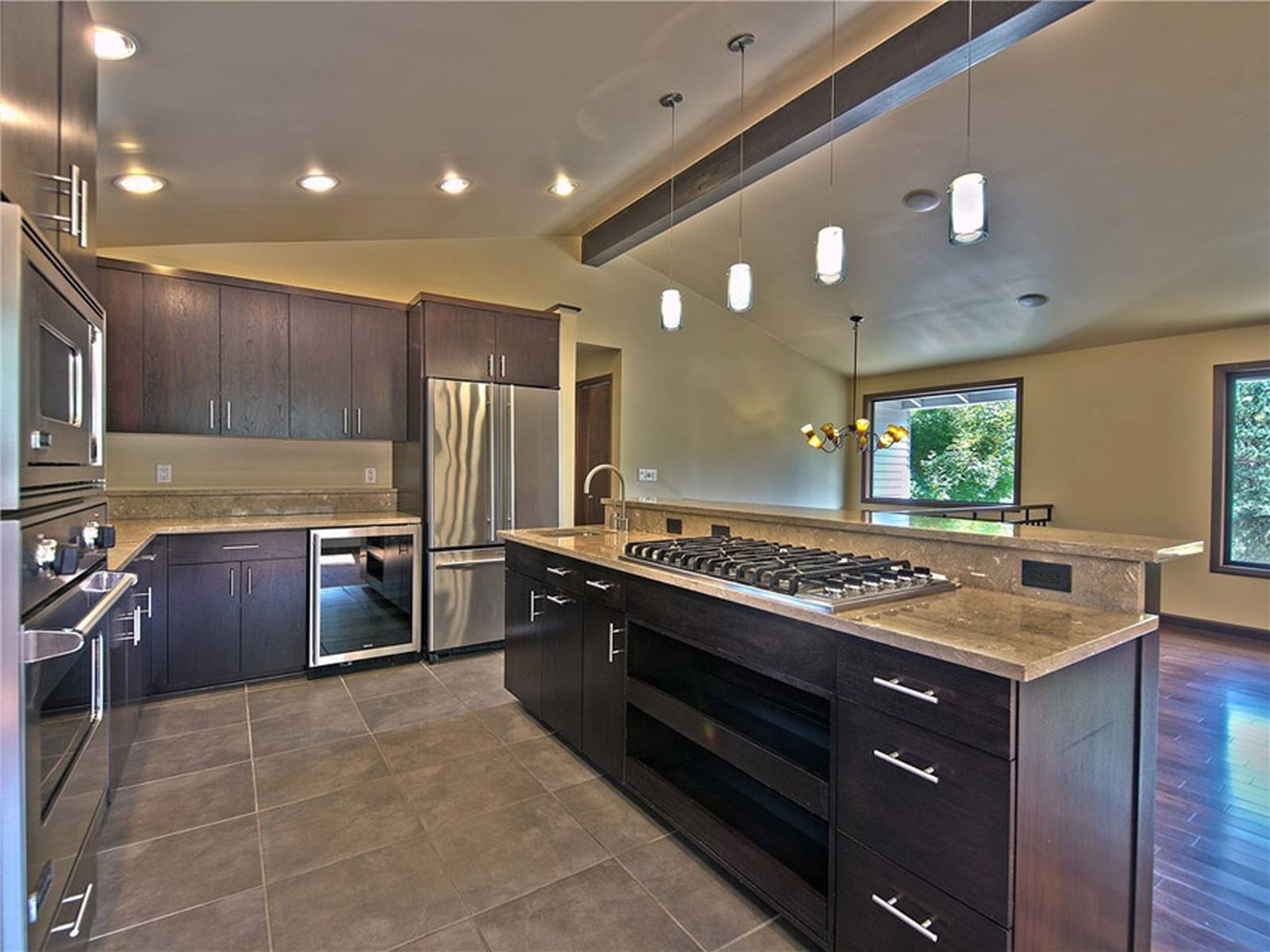 Kitchen with open layout, limestone flooring and dark cabinetry