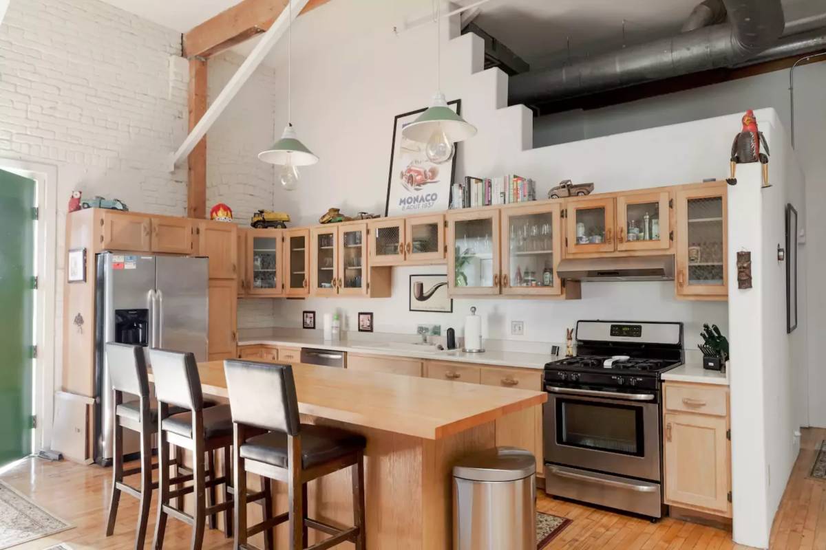 Urban loft kitchen design with wooden furniture and builtin freezer.